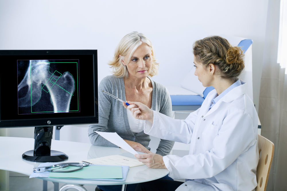 middle aged female patient and her doctor discussing Hormone Therapy for Osteoporosis and Bone Health while looking at x-rays
